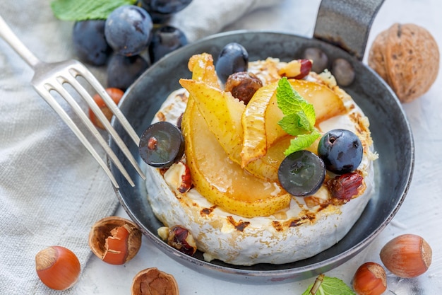 Skillet with baked camembertcaramelized pears and grapes