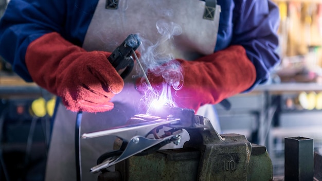 Skillful metal worker working with arc welding machine in factory Sparks fly