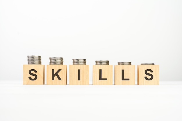 Photo skills text written on wooden block with stacked coins on white background business concept