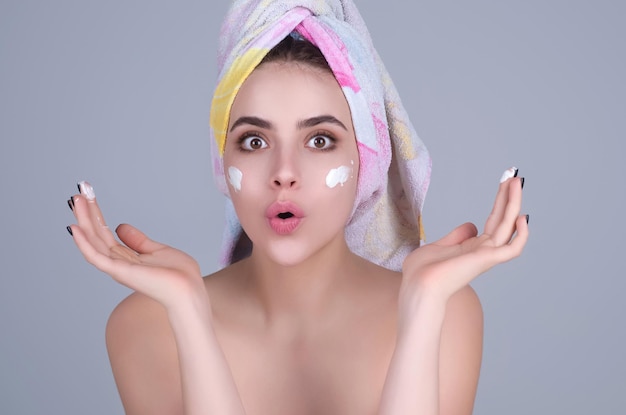 Skin care beauty portrait of a beautiful woman applying face cream isolated on studio background you