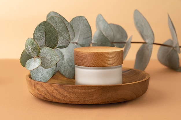 Skin care packaging with cream staying in the wooden plateEucalyptus branch behind