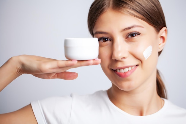 Skin care, woman with beauty face holding facial skin cream.