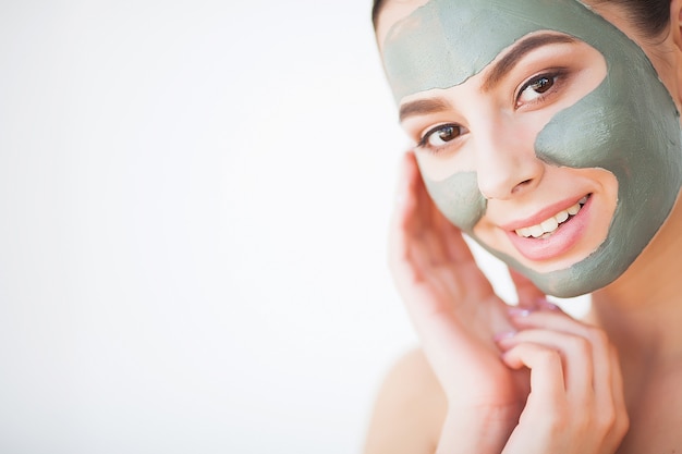 Skin Care. Young Woman With Cosmetic Clay Mask Holding Cucumber At Her Bathroom