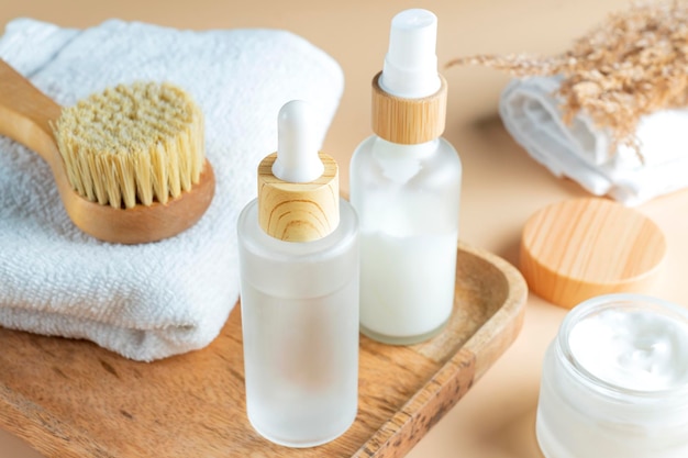 Skin exfolation and rejuvination concept Drop bottle with fruit peeling face mask and face massaging brush with natural bristle on wooden tray with cotton towel Spa concept