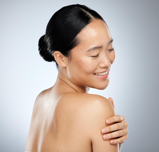 Skincare beauty and body care with a model asian woman in studio on a gray background for natural wellness Cosmetic treatment and skin care with an attractive woman posing to promote a product