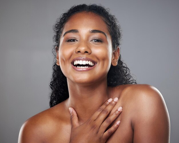 Skincare beauty and portrait of a happy woman in a studio with a cosmetic makeup routine Happiness facial and natural face of a young model with a smile from Mexico isolated by a gray background