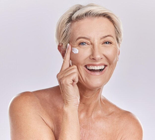 Photo skincare beauty and wellness cream of happy senior woman with smile for skin care on her face in a studio background portrait of a mature model lady in beauty wellness and health and cosmetics