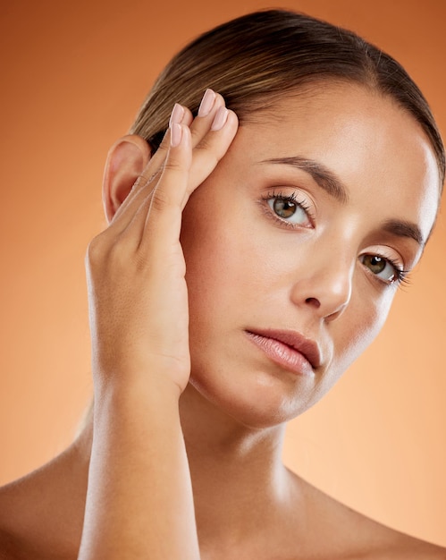 Skincare beauty and woman with makeup for face against an orange studio background Young clean and portrait of a girl model with body wellness healthy cosmetics and care for facial health