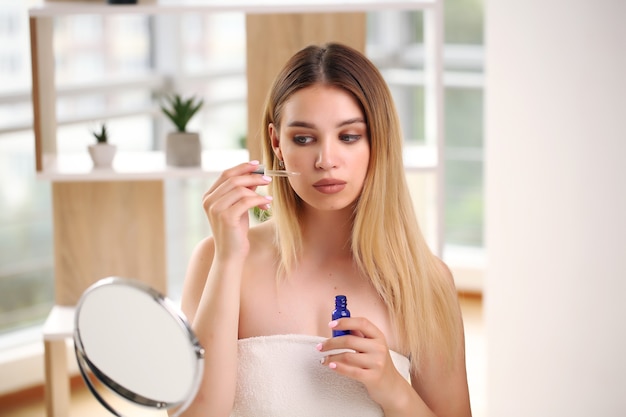 Skincare concept portrait of happy female applying cosmetic.