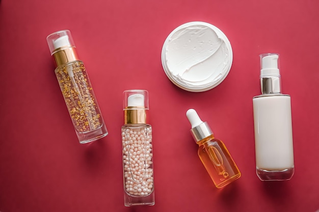 Skincare cosmetics and antiaging beauty products luxury skin care bottles oil serum and face cream on coral background