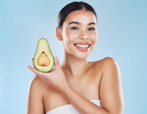 Skincare health and avocado with a woman portrait on studio blue background and mockup Young model with healthy fruit nutrition for face skin care ingredients and clean perfect or natural results