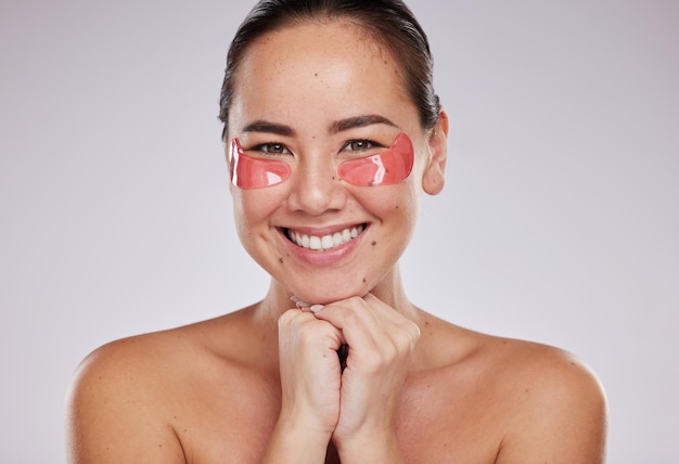 Skincare portrait and asian woman with eye pad on face for anti aging facial on studio background Beauty cosmetics and lady with collagen mask or patches on eyes for fresh skin smile and wellness