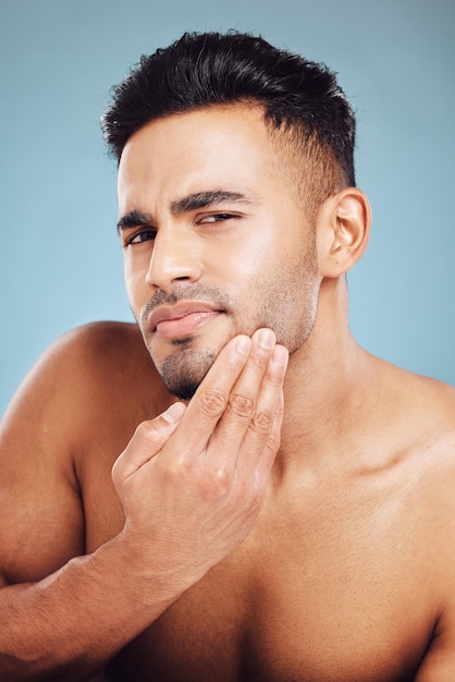 Skincare portrait and man in blue studio thinking of facial hair wellness health and cosmetics beauty glow Young sexy and face model with beard growth idea for skin care self love or dermatology