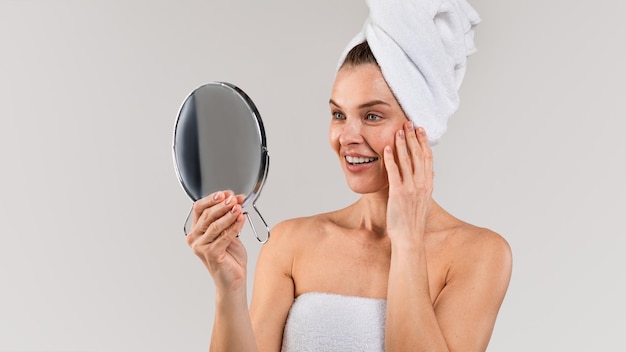 Skincare Treatments Middle aged lady with towel on head looking in mirror