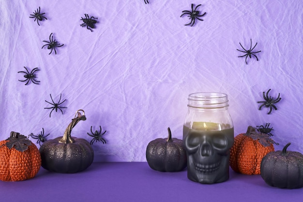 Skull candle black pumpkins and cobweb with spiders on purple background Halloween party decorations