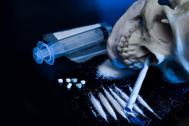 A skull is smoking on a table with pills and pills.