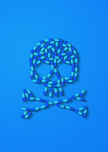 Skull made of capsule pills isolated on blue background. 3D illustration