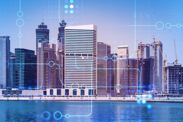 Skyscrapers of Dubai business downtown International hub of trading and financial services Technology theme icons hologram Fintech concept Double exposure Dubai Canal waterfront