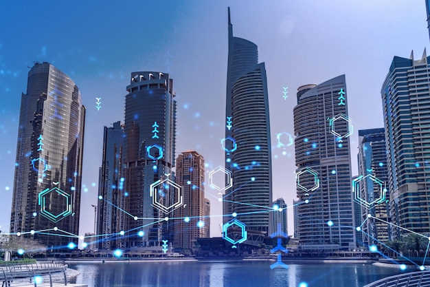 Skyscrapers of Dubai business downtown International hub of trading and financial services Technology theme icons hologram Fintech concept Double exposure Dubai Canal waterfront