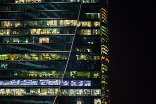 Skyscrapers windows of Moscow-city downtown business center with tall buildings at night. Illuminated windows of business office center. Late night overtime in a modern office building.