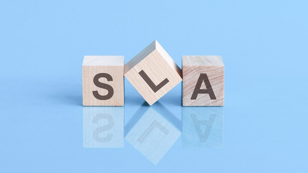 Photo sla word is made of wooden cubes lying on the blue table, business concept. sla short for service level agreement