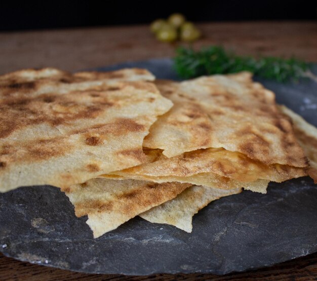 Slate plate on a wooden table with pane carasau olives aromatic herbs Italian cuisine and gastronomy