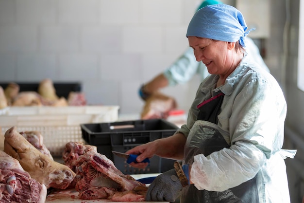 Slaughterhouse Workers in the meat shop at work Woman butcher cuts pork carcasses with a knife