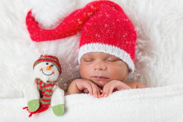 Sleeper newborn baby in a Christmas Santa cap