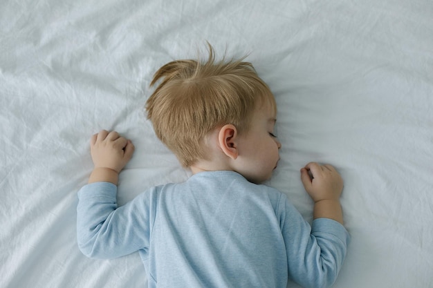 Sleeping adorable baby boy in bed with pacifier in the mouth