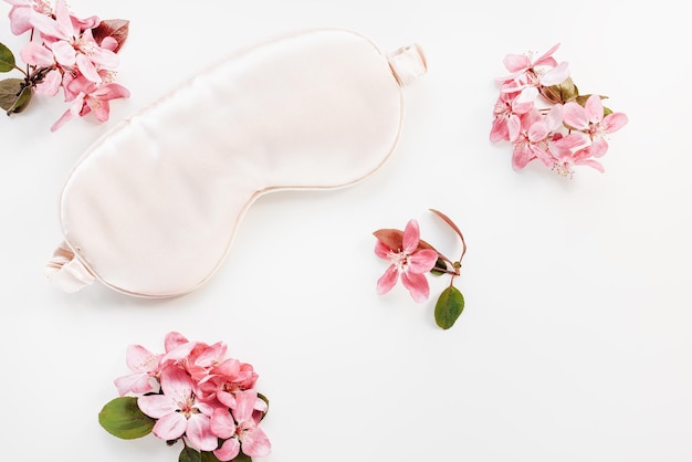 Sleeping mask and spring flowers on white backgrount copy space Beauty sleep concept