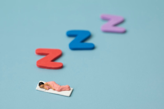 Sleeping miniature woman on blue background