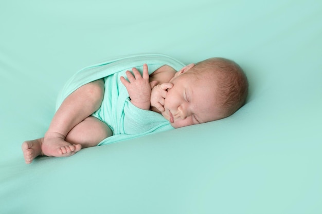 Sleeping newborn baby wrapped on mint background