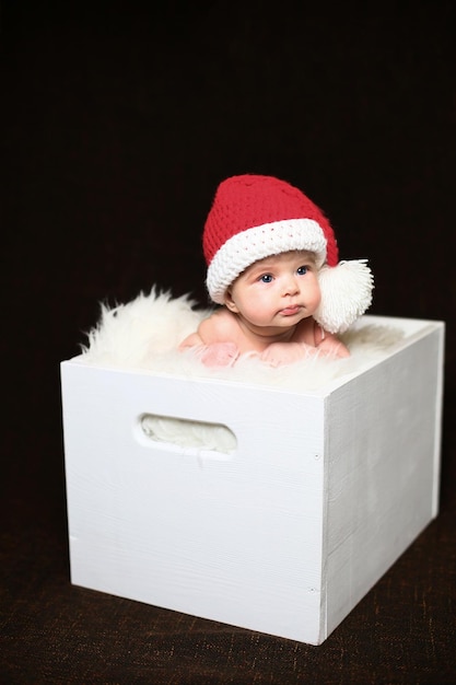 Sleeping two week old newborn baby boy wearing a crocheted Santa hat with snowman plush toy