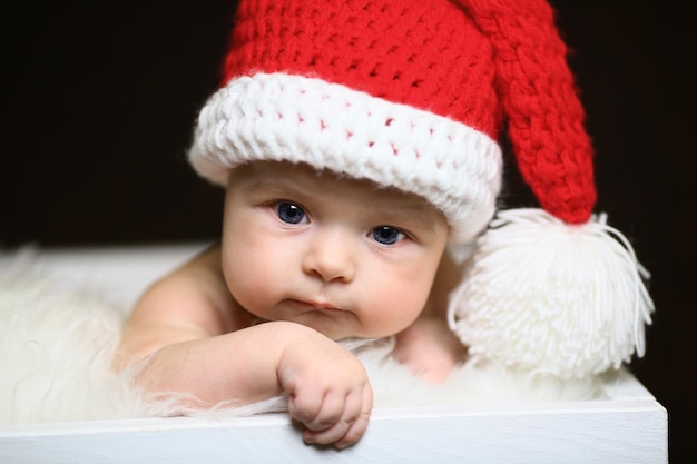 Sleeping two week old newborn baby boy wearing a crocheted Santa hat with snowman plush toy