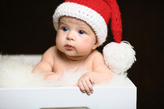 Sleeping two week old newborn baby boy wearing a crocheted Santa hat with snowman plush toy