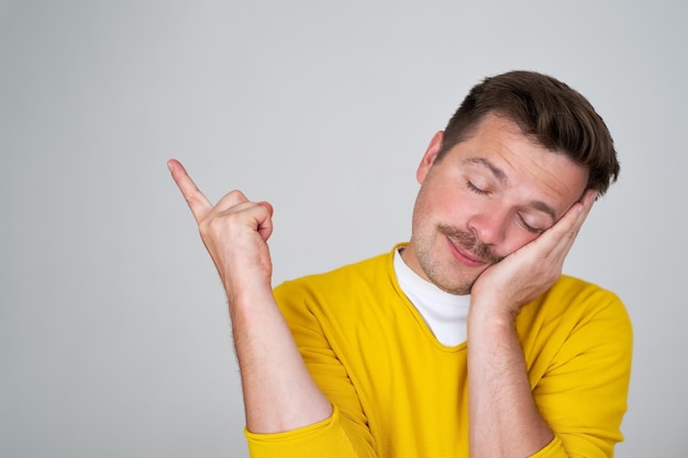 Sleepy guy leaning on palm closing eyes and sleeping pointing aside