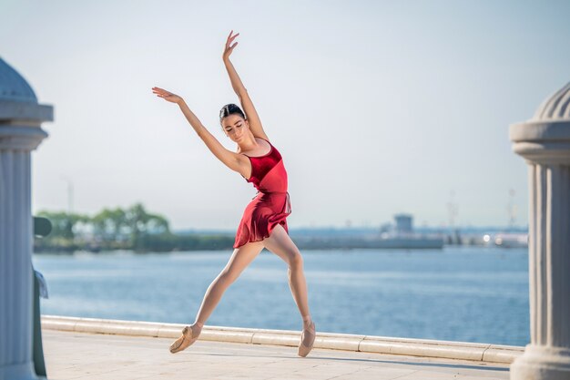 Slender ballerina in pointe shoes and bridal costume is jumping against the background of sea