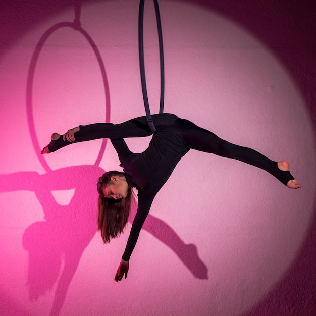 A slender brunette girlan air acrobat in a red suit with long hair  performs exercises in an air r