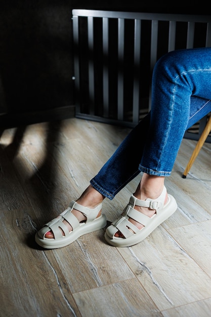 Slender female legs in beige leather sandals without heels Collection of women's summer sandals