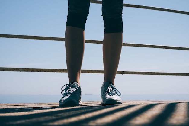 Slender female legs in blue sneakers in the morning sun