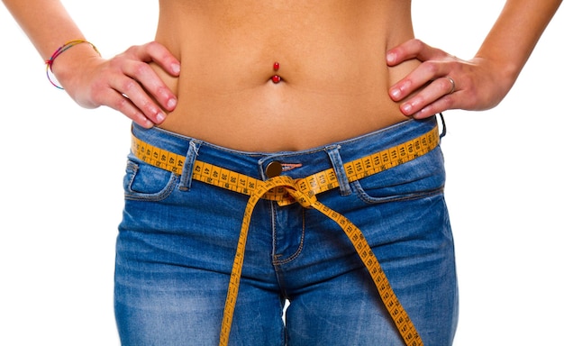 A slender young woman in jeans with a tape measure after a successful diet