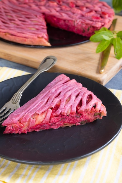 A slice of beet cake on a black plate with a fork next to it.