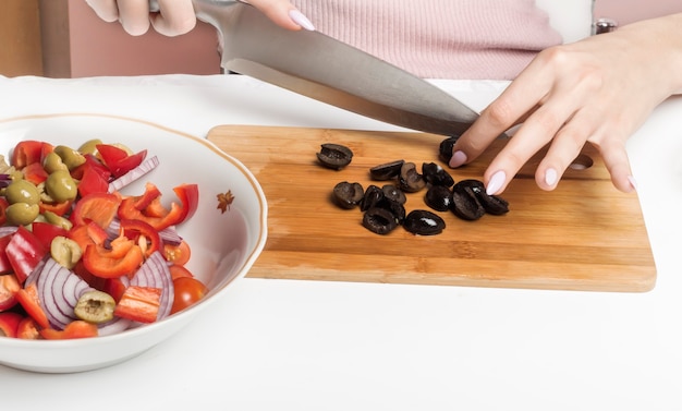 Slice black olives on a cutting Board to add to the salad.