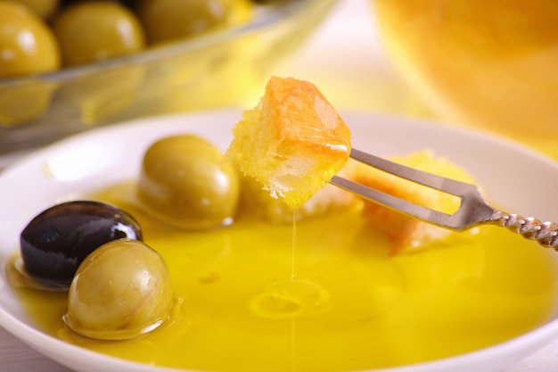 A slice of bread on a fork soaked in olive oil, close-up