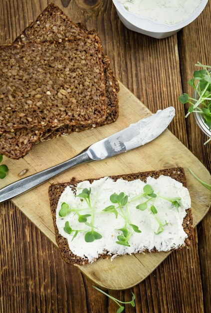 Slice of bread with fresh cutted cress and cream cheese on an old wooden table