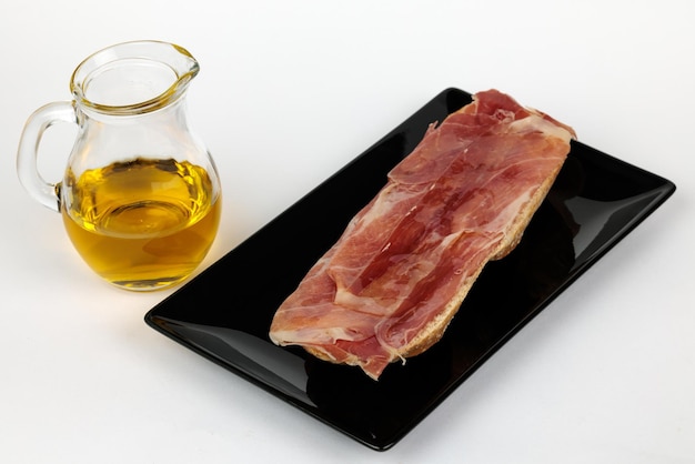 Slice of bread with ham and olive oil.