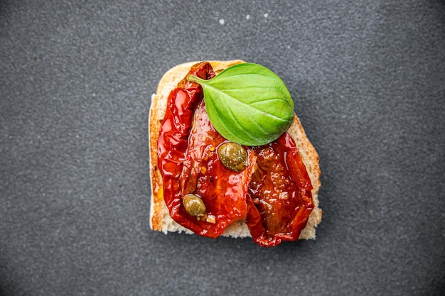 A slice of bread with a tomato and basil leaf on top