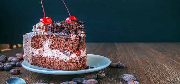 Slice of chocolate cheesecake on plate and cocoa beans on wooden table above view over a rustic