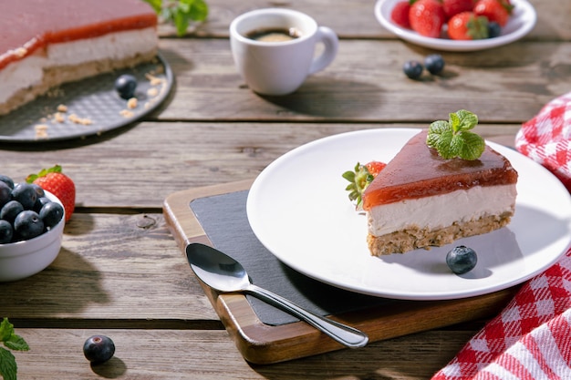 Slice of classical cheesecake served on white plate on wooden table. Selective focus.