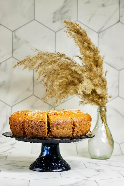 slice of delicious coconut bundt cake in stand cake with reeds vase near hexagon wall